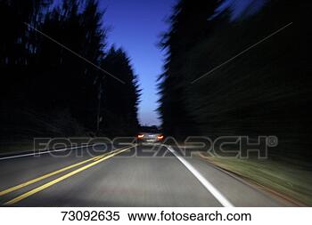 Stock Image - car driving through 
trees at dusk, 
rear view (blurred 
motion). fotosearch 
- search stock 
photos, pictures, 
images, and photo 
clipart