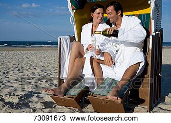 Stock Photo - couple sitting 
in beach shelterman 
pouring champagne 
into flute. fotosearch 
- search stock 
photos, pictures, 
images, and photo 
clipart