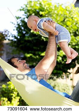 Stock Photo - father lying in 
hammock,  laughing, 
 lifting baby 
son (3-6 months). 
fotosearch - search 
stock photos, 
pictures, images, 
and photo clipart