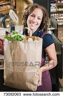 Stock Photo - female cashier 
holding carrier 
bag, smiling, 
portrait. fotosearch 
- search stock 
photos, pictures, 
images, and photo 
clipart