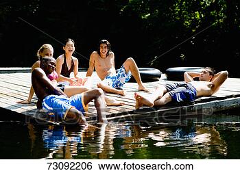 Stock Photo - five young people 
in swimwear, sitting 
on wooden platform, 
portrait. fotosearch 
- search stock 
photos, pictures, 
images, and photo 
clipart