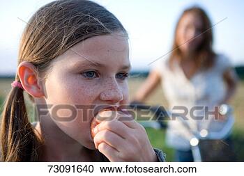 Stock Photography - girl (8-9) biting 
applemother with 
bicycle in backgroundclose-up. 
fotosearch - search 
stock photos, 
pictures, images, 
and photo clipart