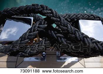 Stock Photo - heavy black rope 
coiled around 
two stainless 
steel bollards. 
fotosearch - search 
stock photos, 
pictures, images, 
and photo clipart