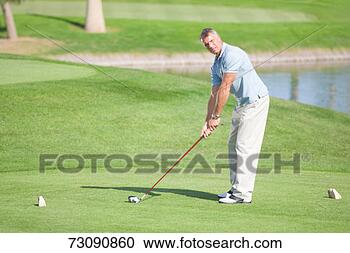 Stock Photography - male golfer teeing 
off on golf course. 
fotosearch - search 
stock photos, 
pictures, images, 
and photo clipart