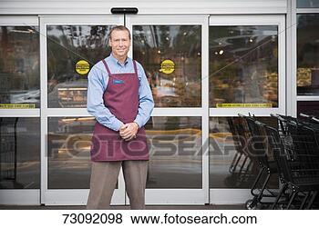 Stock Photo - male shop assistant 
standing in front 
of shop doors, 
portrait. fotosearch 
- search stock 
photos, pictures, 
images, and photo 
clipart