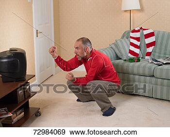 Stock Photograph - mature football 
supporter watching 
television and 
raising fists 
with. fotosearch 
- search stock 
photos, pictures, 
images, and photo 
clipart
