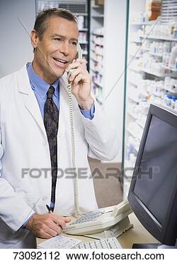 Stock Photo - mature male pharmacist, 
standing, talking 
on telephone. 
fotosearch - search 
stock photos, 
pictures, images, 
and photo clipart