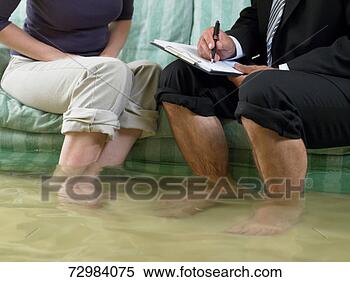 Stock Image - mature man and 
mid adult woman 
sitting on sofa 
with water over 
their. fotosearch 
- search stock 
photos, pictures, 
images, and photo 
clipart