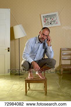 Stock Photo - mature man using 
mobile phone crouching 
on chair in flooded 
living. fotosearch 
- search stock 
photos, pictures, 
images, and photo 
clipart