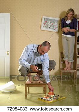 Stock Photo - mature man using 
mobile phone crouching 
on chair in flooded 
living. fotosearch 
- search stock 
photos, pictures, 
images, and photo 
clipart