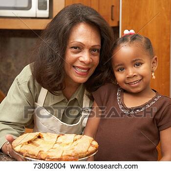Stock Photo - mother and daughter 
(3-5) smiling 
in kitchen, holding 
pie, portrait. 
fotosearch - search 
stock photos, 
pictures, images, 
and photo clipart