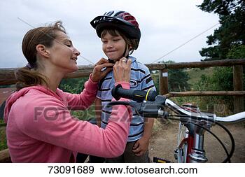 Stock Photograph - mother fastening 
son's (6-7) cycling 
helmet. fotosearch 
- search stock 
photos, pictures, 
images, and photo 
clipart