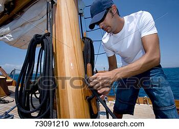 Stock Photography - sailboat crewman 
fastening rope 
to mast. fotosearch 
- search stock 
photos, pictures, 
images, and photo 
clipart