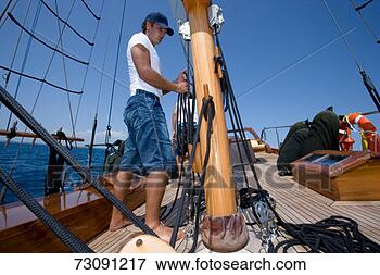 Picture - sailboat crewman 
fastening rope 
to mast. fotosearch 
- search stock 
photos, pictures, 
images, and photo 
clipart