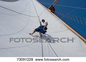 Stock Photo - sailboat crewman 
suspended from 
mast against sail, 
view from below. 
fotosearch - search 
stock photos, 
pictures, images, 
and photo clipart
