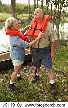 Picture - senior couple 
by water, woman 
adjusting husband's 
life jacket. fotosearch 
- search stock 
photos, pictures, 
images, and photo 
clipart