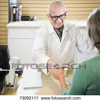 Picture - senior male pharmacist 
smiling, taking 
credit card from 
senior woman. 
fotosearch - search 
stock photos, 
pictures, images, 
and photo clipart