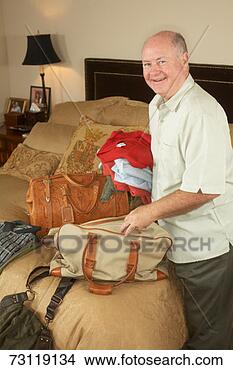 Stock Photo - senior man packing 
bags for trip, 
portrait. fotosearch 
- search stock 
photos, pictures, 
images, and photo 
clipart
