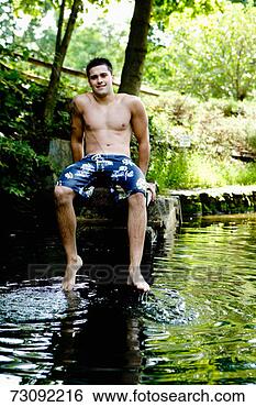 Stock Photo - teenage boy (17-19), 
sitting on wall, 
dipping toes in 
water portrait. 
fotosearch - search 
stock photos, 
pictures, images, 
and photo clipart