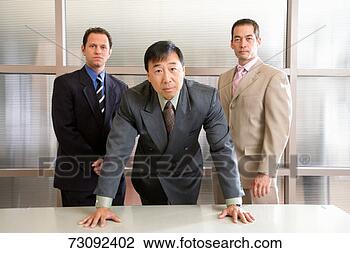 Stock Photo - three businessmen 
in office, one 
leaning on desk, 
portrait. fotosearch 
- search stock 
photos, pictures, 
images, and photo 
clipart