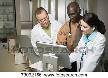 Stock Photo - three doctors 
consulting computer 
screen at nurse's 
station. fotosearch 
- search stock 
photos, pictures, 
images, and photo 
clipart