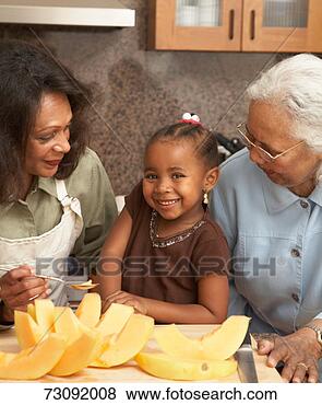 Stock Photo - three generation 
family in kitchen, 
 smiling,  melon 
slices on. fotosearch 
- search stock 
photos, pictures, 
images, and photo 
clipart