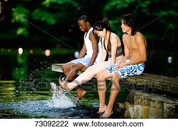 Stock Photo - three young people 
sitting on diving 
board, kicking 
feet in water. 
fotosearch - search 
stock photos, 
pictures, images, 
and photo clipart