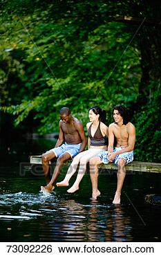Stock Photo - three young people 
sitting on diving 
board, kicking 
feet in water. 
fotosearch - search 
stock photos, 
pictures, images, 
and photo clipart