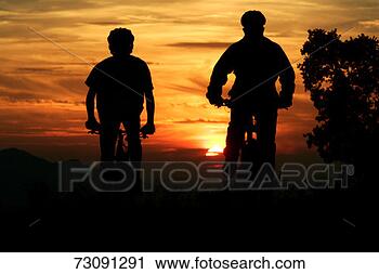 Stock Photography - two teenage boys 
riding bikes at 
sunset, silhouette. 
fotosearch - search 
stock photos, 
pictures, images, 
and photo clipart