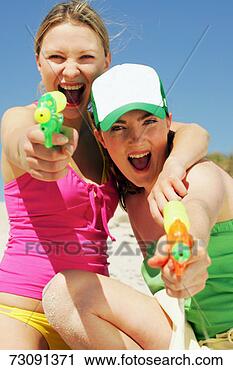 Stock Photography - two young women 
firing water pistols, 
outdoors, portrait. 
fotosearch - search 
stock photos, 
pictures, images, 
and photo clipart