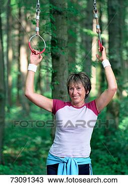Stock Photo - woman holding 
gymnastic rings 
in forest, portrait. 
fotosearch - search 
stock photos, 
pictures, images, 
and photo clipart