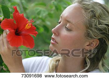 Stock Photo - woman looking 
at red hibiscus 
flower outdoors, 
close-up. fotosearch 
- search stock 
photos, pictures, 
images, and photo 
clipart