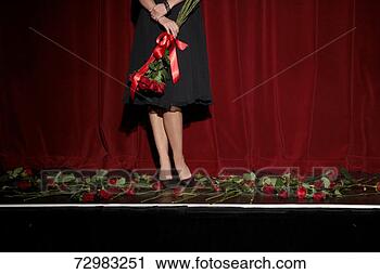 Stock Photography - woman standing 
on theatre stage 
holding flowers, 
low section. fotosearch 
- search stock 
photos, pictures, 
images, and photo 
clipart