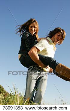 Stock Photo - young man giving 
young woman piggy 
back in field. 
fotosearch - search 
stock photos, 
pictures, images, 
and photo clipart