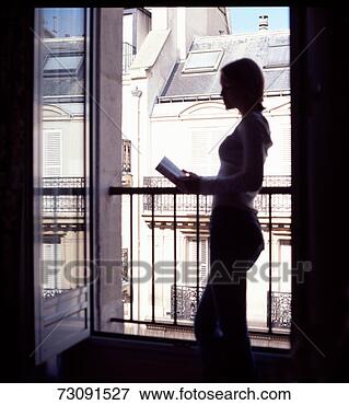 Picture - young woman reading 
at balcony in 
apartment, profile 
(back lit). fotosearch 
- search stock 
photos, pictures, 
images, and photo 
clipart