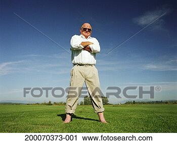 Stock Photography - mature man standing 
barefoot in grass, 
arms folded across 
chest. fotosearch 
- search stock 
photos, pictures, 
images, and photo 
clipart