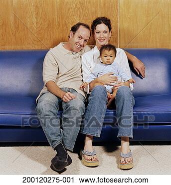 Stock Photography - couple sitting 
on sofa holding 
adopted baby girl 
(9-12 months). 
fotosearch - search 
stock photos, 
pictures, images, 
and photo clipart