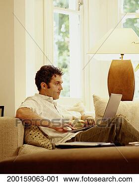 Stock Photography - man using laptop 
on sofa, side 
view. fotosearch 
- search stock 
photos, pictures, 
images, and photo 
clipart
