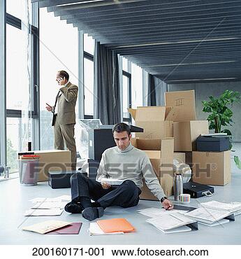 Stock Photography - two businessmen 
in office, one 
reading paperwork 
against box on 
floor. fotosearch 
- search stock 
photos, pictures, 
images, and photo 
clipart