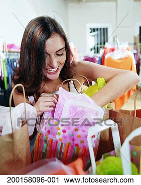 Stock Photography - young woman reaching 
into shopping 
bag in retail 
store, smiling. 
fotosearch - search 
stock photos, 
pictures, images, 
and photo clipart