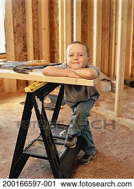 Stock Photography - boy (5-7) leaning 
on slat of wood 
across sawhorse, 
smiling, portrait. 
fotosearch - search 
stock photos, 
pictures, images, 
and photo clipart