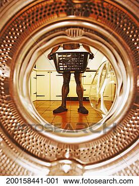 Stock Photography - man wearing shorts, 
holding basket 
of washing, view 
from drum interior. 
fotosearch - search 
stock photos, 
pictures, images, 
and photo clipart