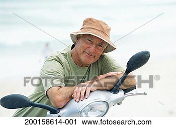 Stock Photography - senior man sitting 
on motor scooter 
on beach, portrait. 
fotosearch - search 
stock photos, 
pictures, images, 
and photo clipart
