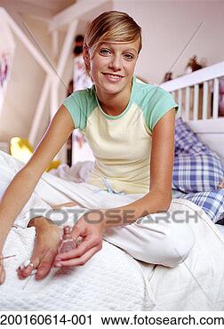 Stock Photography - teenage girl (13-15) 
on bed, holding 
nail polish, smiling, 
portrait. fotosearch 
- search stock 
photos, pictures, 
images, and photo 
clipart
