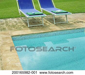 Stock Photography - towels, book and 
sun cream placed 
on sun loungers 
at edge of pool. 
fotosearch - search 
stock photos, 
pictures, images, 
and photo clipart