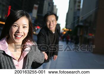 Stock Photography - young couple holding 
hands on urban 
sidewalk (focus 
on woman). fotosearch 
- search stock 
photos, pictures, 
images, and photo 
clipart