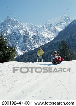 Stock Photography - boy and girl (9-13) 
sledding down 
hill, woman watching 
from top of hil. 
fotosearch - search 
stock photos, 
pictures, images, 
and photo clipart