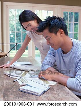 Stock Photography - couple working 
on finances at 
home, smiling. 
fotosearch - search 
stock photos, 
pictures, images, 
and photo clipart