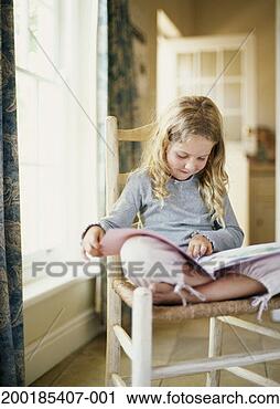 Stock Photography - girl (5-7) sitting 
cross-legged on 
chair, reading 
book. fotosearch 
- search stock 
photos, pictures, 
images, and photo 
clipart