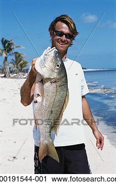 Stock Photography - man holding speared 
mutton snapper 
on beach. fotosearch 
- search stock 
photos, pictures, 
images, and photo 
clipart